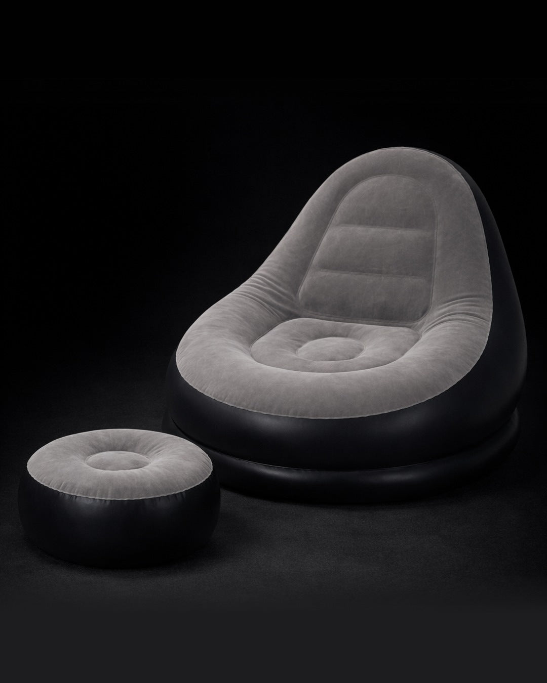 Sillón inflable gris y negro con puf reposapiés a juego sobre fondo oscuro